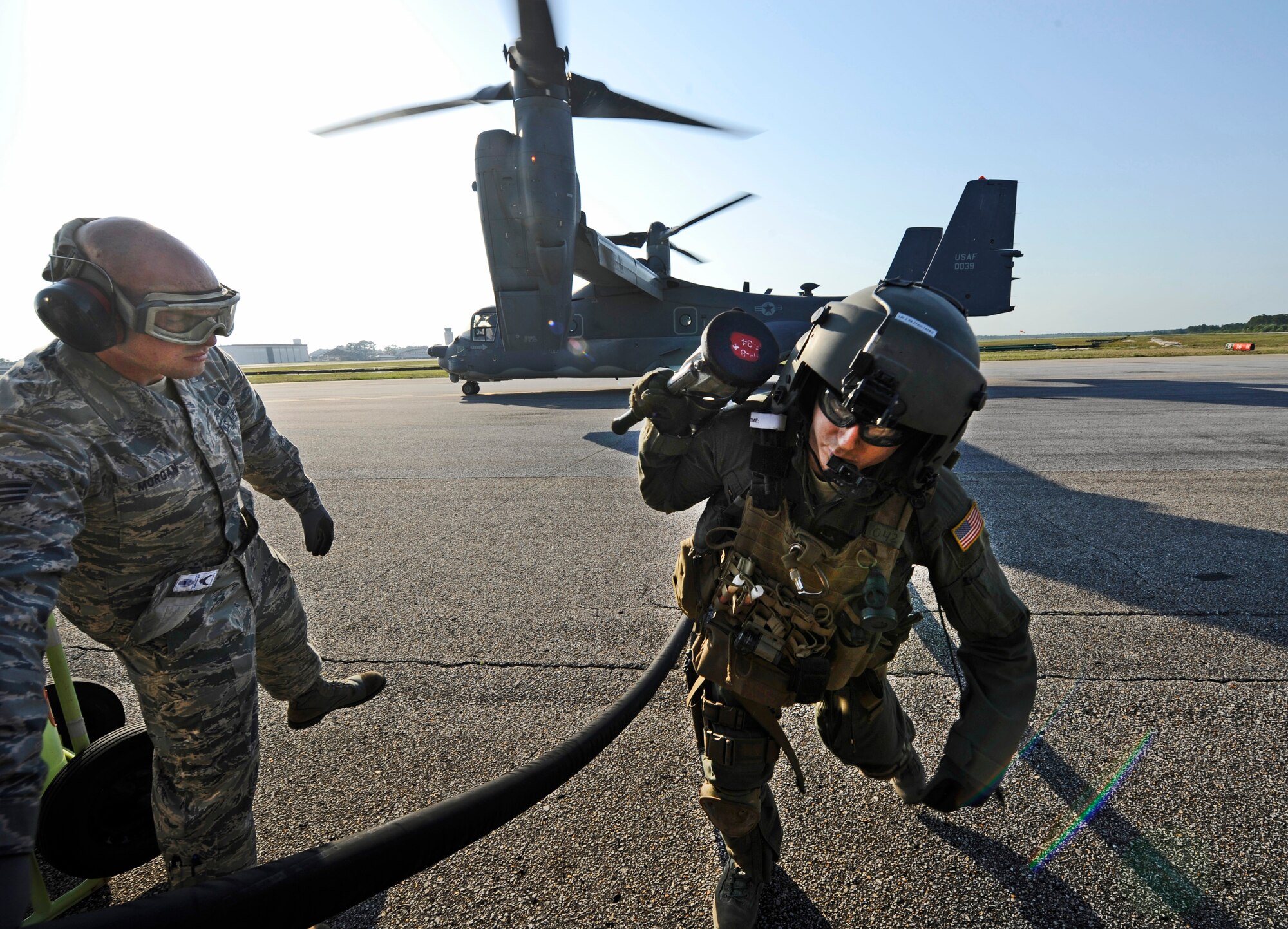Senior Airman Johnathan Morgan, 1st Special Operations Logistics Readiness Squadron fuels journeyman, assists a CV-22 Osprey crew chief with a fuel hose at Hurlburt Field, Fla., May 20, 2014. The Osprey had to be refueled prior to its training mission. (U.S. Air Force photo/Staff Sgt. Jeff Andrejcik)