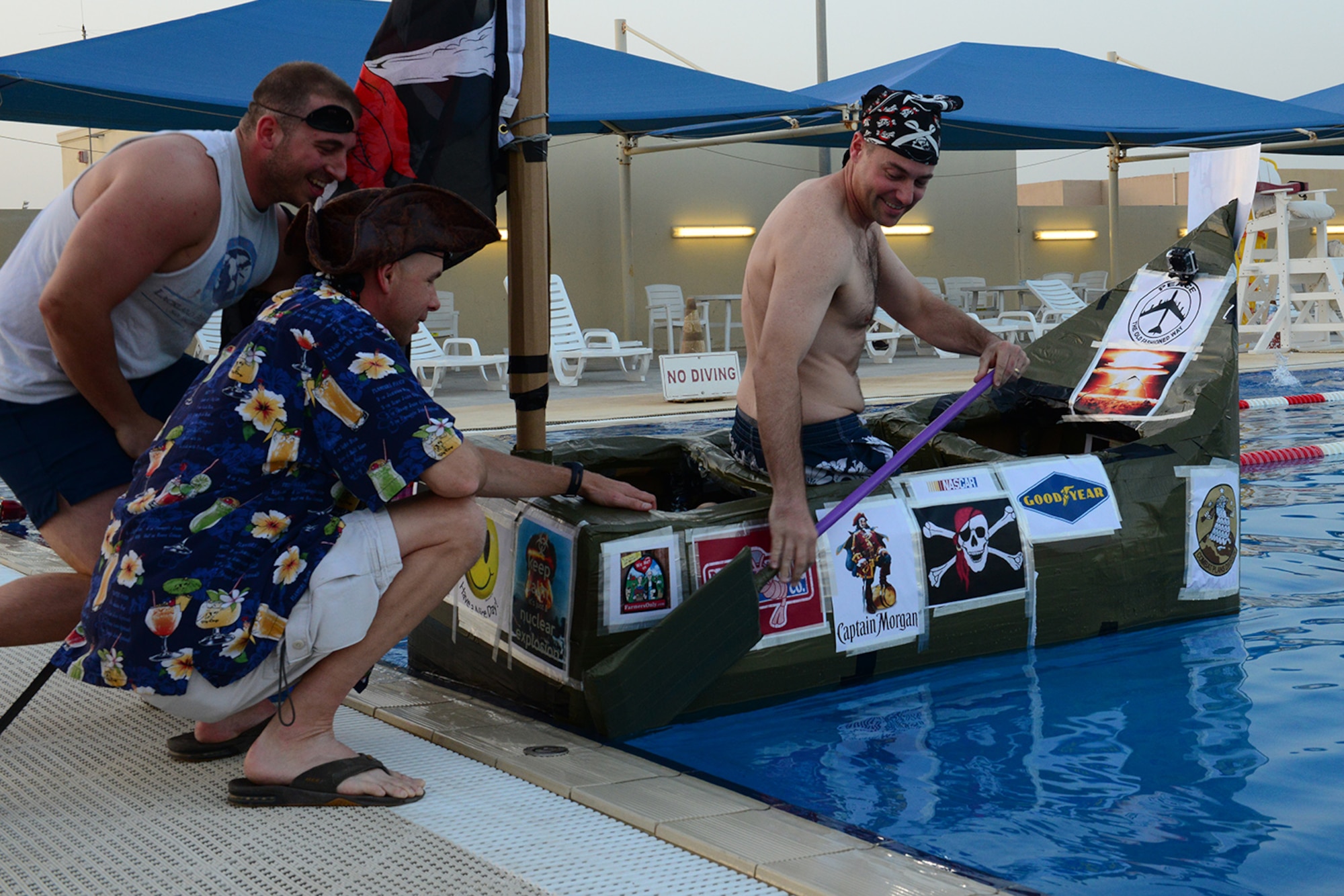 U.S. Air Force Airmen help their teammate into their cardboard boat at a cardboard boat regatta at Al Udeid Air Base, Qatar, May 23, 2014. These regattas started in 2012 and are held periodically, depending on holiday themes and to build morale and camaraderie. (U.S. Air Force photo by Staff Sgt. Ciara Wymbs)