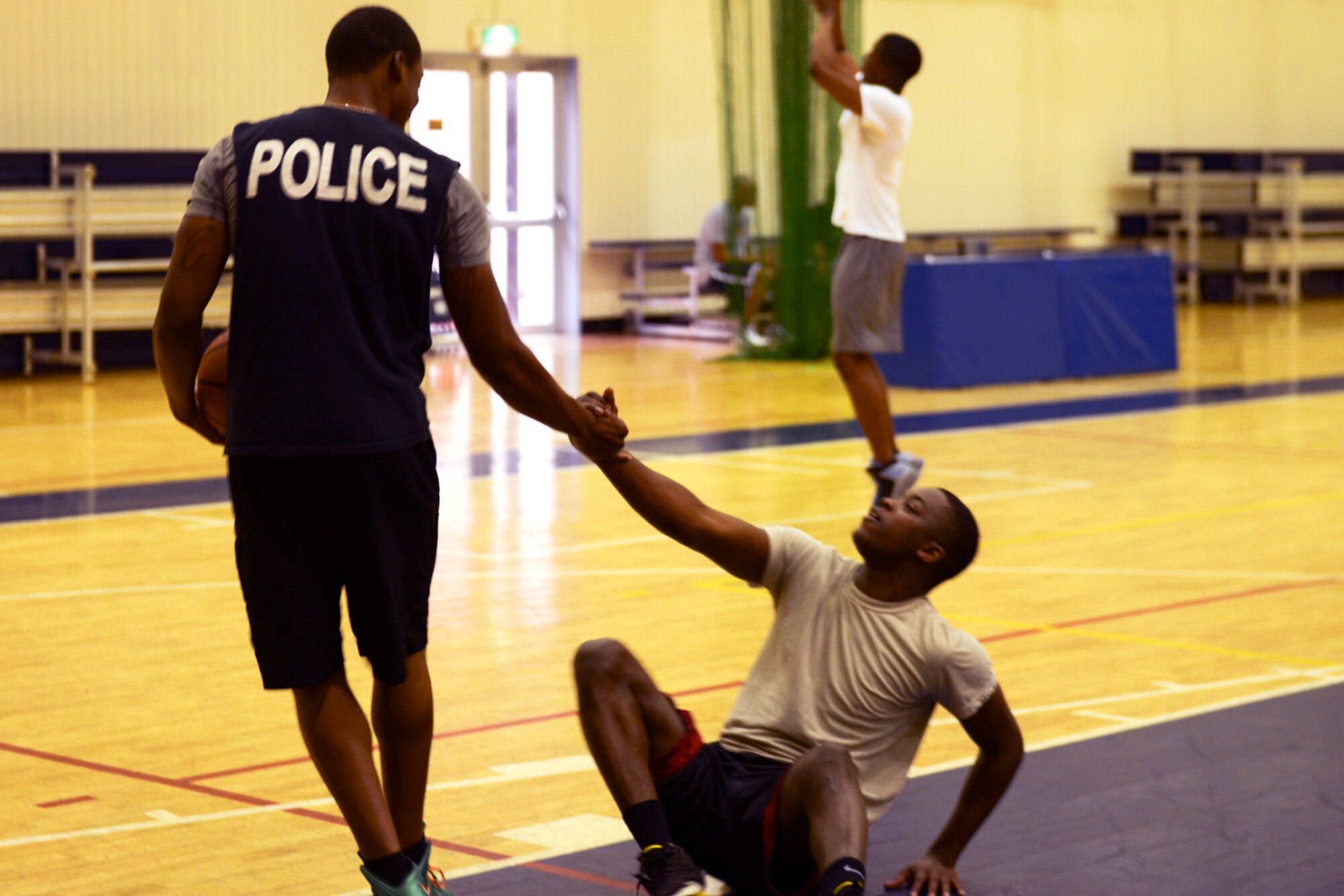 Airman 1st Class Cleveland Greene helps up Senior Airman Darren Fields, both 374th Security Forces Squadron patrolmen, after a fall during a basketball tournament at Yokota Air Base, Japan, May 21, 2014. The basketball tournament held during Police Week served as a teambuilding exercise and a morale booster. (U.S. Air Force photo by Airman 1st Class David Danford/Released)