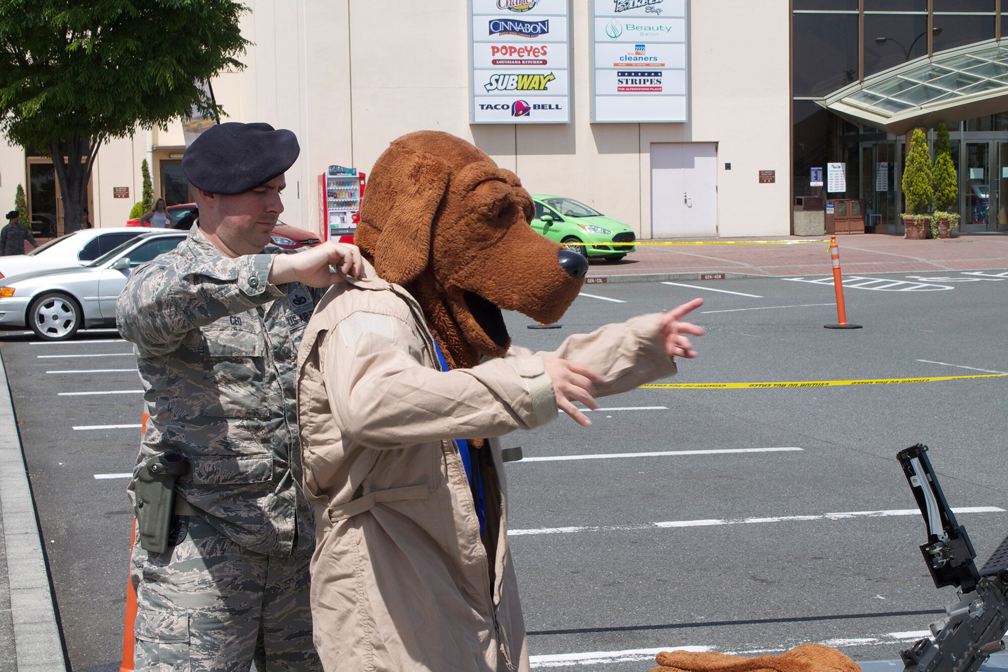 Staff Sgt. Stephen Ceo, 374th Security Forces Squadron assistant NCO in charge of Combat Arms, helps an Airmen into a 'McGruff the Crime Dog' costume at Yokota Air Base, Japan, May 19, 2014. Yokota celebrated the contributions of Security Forces members through a variety of Police Week themed events. (U.S. Air Force photo by Airman 1st Class David Danford/Released)