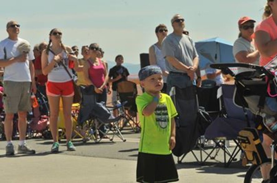 Spectators hold their hands on their hearts during the entrance of the Golden Knights while the National Anthem plays during SkyFest 2014 open house and air show at Fairchild Air Force Base, Wash., May 31, 2014. An estimated 150,000 people attended the two-day air show which included numerous static aircraft and demonstrations by the AF Thunderbirds and the Army Golden Knights. (U.S. Air Force photo by Staff Sgt. Veronica Montes/Released)