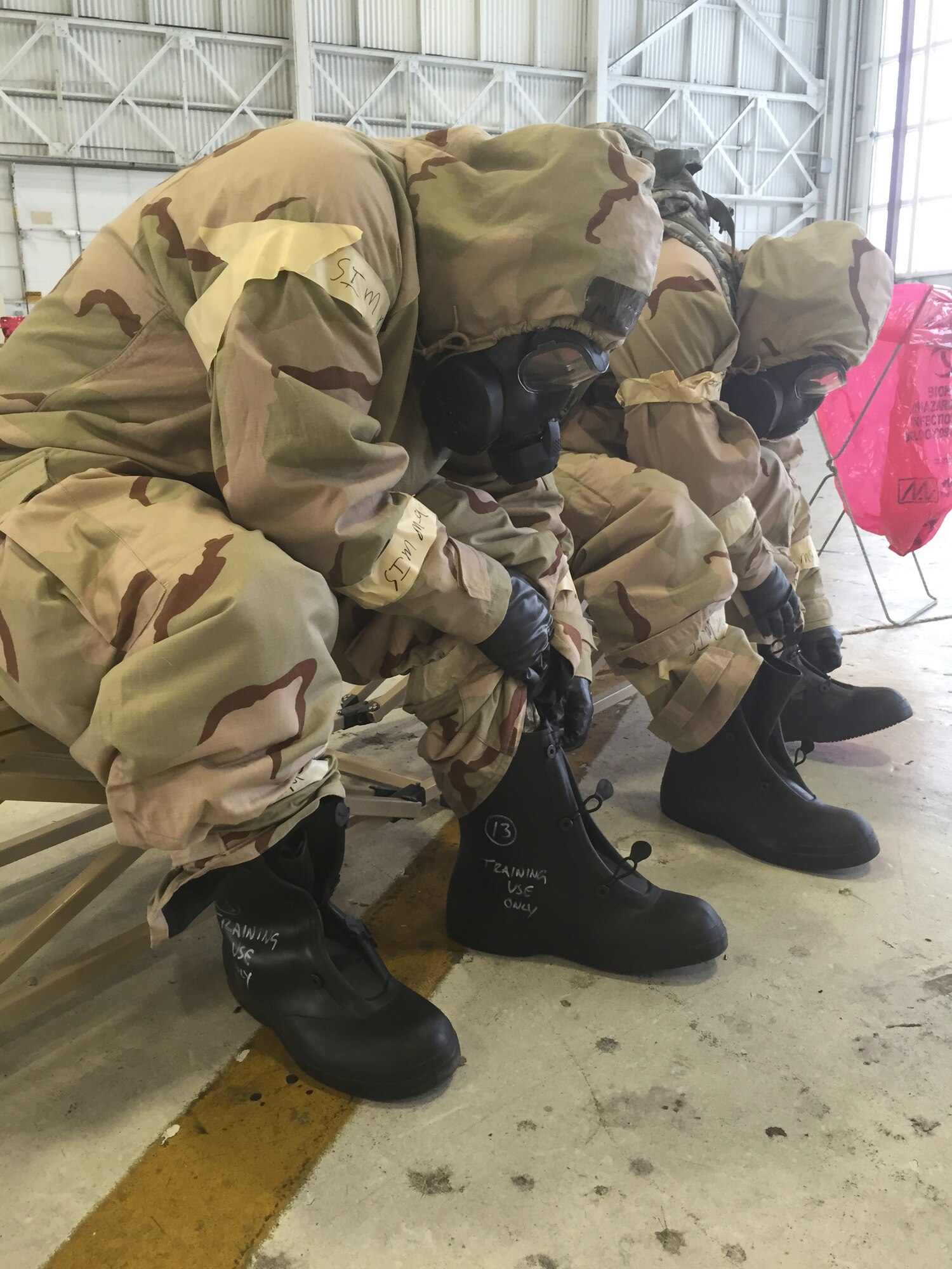 Reservists from the 920th Rescue Wing, Patrick Air Force Base, Fla., remover their over-boots at a station in a simulated decontamination line during a chemical warfare training session November 1, 2014. (U.S. Air Force photo/Senior Airman Natasha Dowridge)