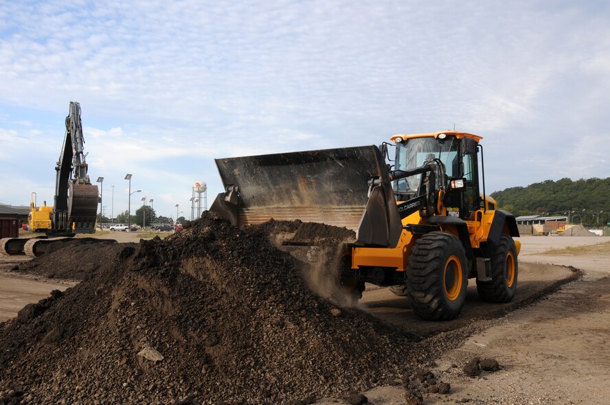 Senior Airman Anthony Anderson operates a JCB front-end loader and Airman Zach Mitchell guides a Volvo excavator during an exercise at Ebbing Air National Guard Base, Fort Smith, Ark., Oct. 5, 2014. Both are members of 188th Civil Engineering Squadron. (U.S. Air National Guard photo by Airman 1st Class Cody Martin/Released)