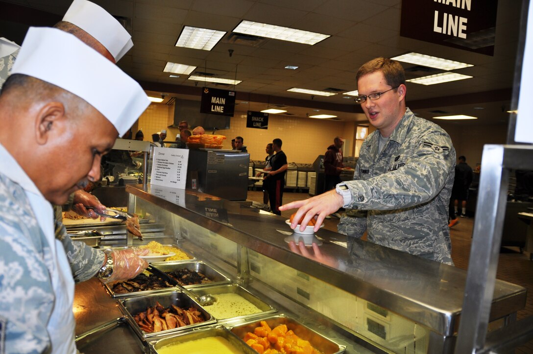 Airman 1st Class Matthew Pfenninger, a cargo ground loader specialist with the 74th Aerial Port Squadron, Joint Base San Antonio-Lackland, Texas receives a serving of yams from Chief Master Sgt. Richard Garcia, 26th Aerial Port Squadron, operations chief, at the Live Oak Dining Facility at Joint Base San Antonio-Lackland Nov. 1, 2014. (U.S. Air Force photo by Tech Sgt. Carlos J. Trevino)

