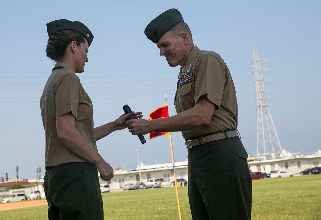 Col. Edward Bligh, right, passes a microphone to Lt. Col Maria McMillen during the redesignation ceremony of 3rd Transportation Support Battalion Oct. 1 at the parade field on Camp Foster. Bligh is from Athens, Pennsylvania, and is the commanding officer for Combat Logistics Regiment 3, 3rd Marine Logistics Group, III Marine Expeditionary Force. McMillen is from Craig, Colorado and is the commanding officer for 3rd TSB, CLR-3.