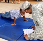 November is Military Family Month. In this 2013 photo, 3-year-old Maurcellus Smith, 3, son of Master Sgt. Jamila Smith, battalion S-2 Shop noncommissioned officer in charge, 728th Military Police Battalion, 8th Military Police Brigade, performs pushups while Sgt. Guipps Laguerre, supply sergeant, Headquarters and Headquarters Detachment, 728th MP Bn., 8th MP Bde. counts and keeps score at Schofield Barracks to celebrate the battalion's military families. 