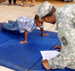 November is Military Family Month. In this 2013 photo, 3-year-old Maurcellus Smith, 3, son of Master Sgt. Jamila Smith, battalion S-2 Shop noncommissioned officer in charge, 728th Military Police Battalion, 8th Military Police Brigade, performs pushups while Sgt. Guipps Laguerre, supply sergeant, Headquarters and Headquarters Detachment, 728th MP Bn., 8th MP Bde. counts and keeps score at Schofield Barracks to celebrate the battalion's military families. 