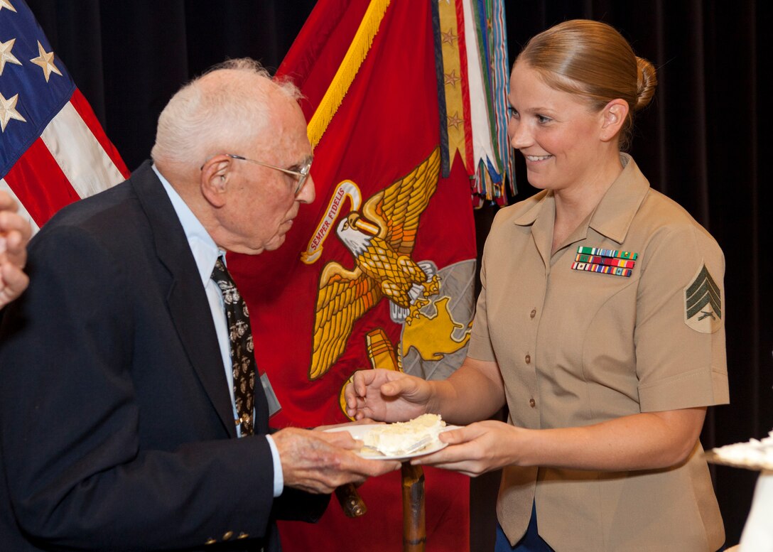 The oldest Marine, retired Maj. Bill Sager, gives a slice of cake to the youngest Marine, Sgt. Christine Bloomfield, during Mack's Marines 239th Marine Corps Birthday Luncheon at Marine Barracks Washington, Washington, D.C., Oct. 30, 2014. (U.S. Marine Corps photo by Cpl. Tia Dufour/Released)