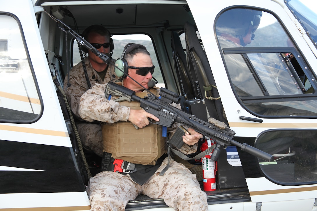 Fourth Marine Division Gunner CWO4 Richard Dunham, positions himself out the side of a Texas Highway Patrol helicopter during aerial sniping practical application at the 9-Mile Training Center in Pecos County, Texas, Sept. 25, 2014. Marine snipers from the 4th Mar. Div. conducted firing exercises that included known and unknown distance 7.62 mm training, night fire, unsupported positions firing, and a team stress shoot.