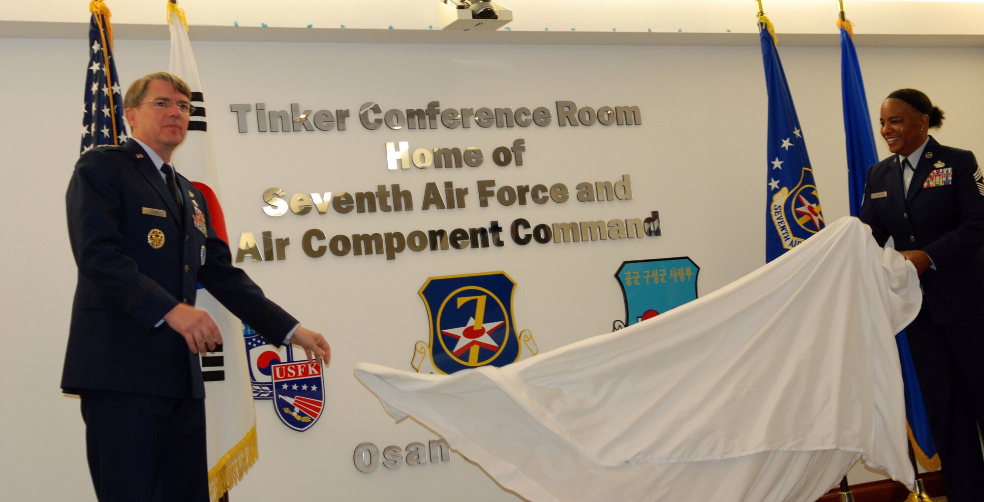 Lt. Gen. Jan-Marc Jouas, 7th Air Force commander and Chief Master Sgt. Shelina Frey, 7th AF command chief, unveil the new designation of the 7th AF conference room Oct. 31, 2014.  The conference room, now the Tinker Conference Room, was dedicated to Maj. Gen. Clarence Tinker, the first commander of 7th AF.  (U.S. Air Force photo by Master Sgt. Marelise Wood)
