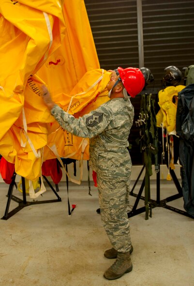 Chief Master Sgt. James Smith, 15th Wing command chief, checks out a life raft hanging in the parachute drying tower during a visit to the 15th Operations Support Squadron Aircrew Flight Equipment Flight at Joint Base Pearl Harbor-Hickam, Hawaii, Oct. 24, 2014. (U.S. Air Force photo by Tech. Sgt. Terri Paden)