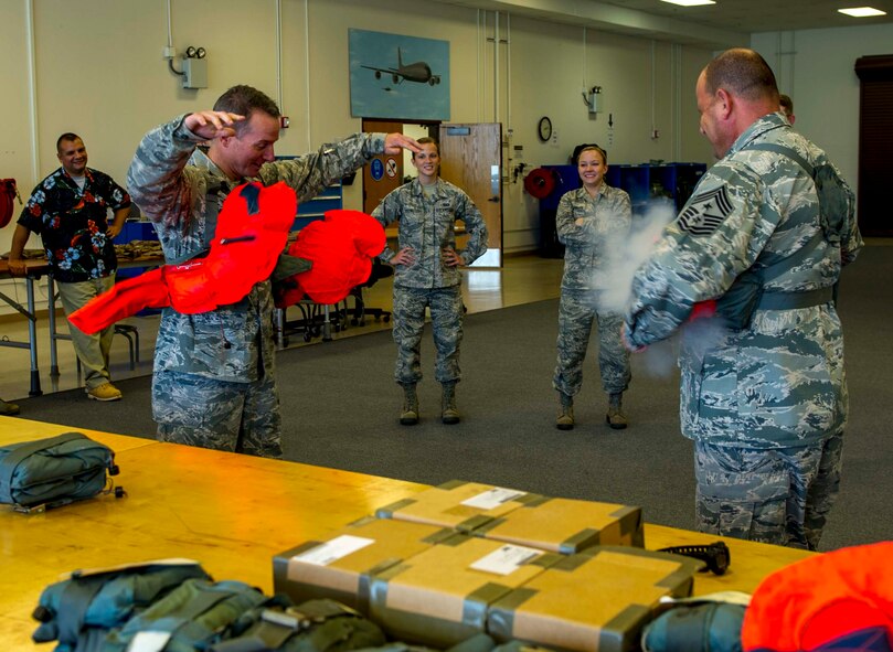Col. Randy Huiss, 15th Wing commander, left, and Chief Master Sgt. James Smith, 15th WG command chief, right, perform a functional test on an LPU-10/P life preserver during their visit to the 15th Operations Support Squadron Aircrew Flight Equipment Flight at Joint Base Pearl Harbor-Hickam, Hawaii, Oct. 24, 2014. (U.S. Air Force photo by Tech. Sgt. Terri Paden)