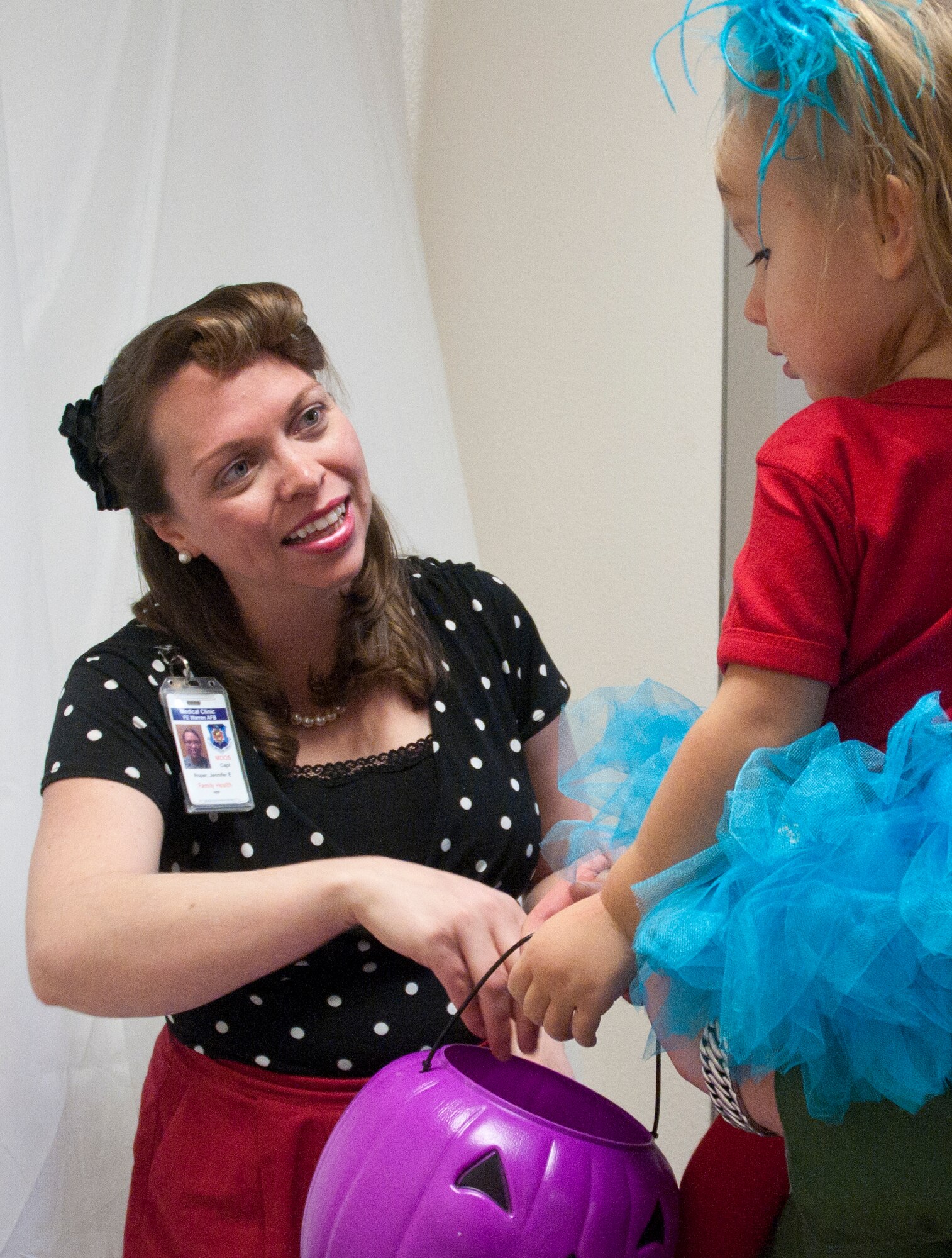 Capt. Jennifer Roper, 90th Medical Operations Squadron, hands candy to Johanna Flanigan, 2, daughter of 1st Lieutenant Mark Flanigan, 90th Operations Group, during the 90th Medical Groups Trick or Treat event in the clinic Oct. 31. During the event each clinic had a different costume theme; Family Health’s theme was the 50s. (U.S. Air Force photo by Airman Malcolm Mayfield)