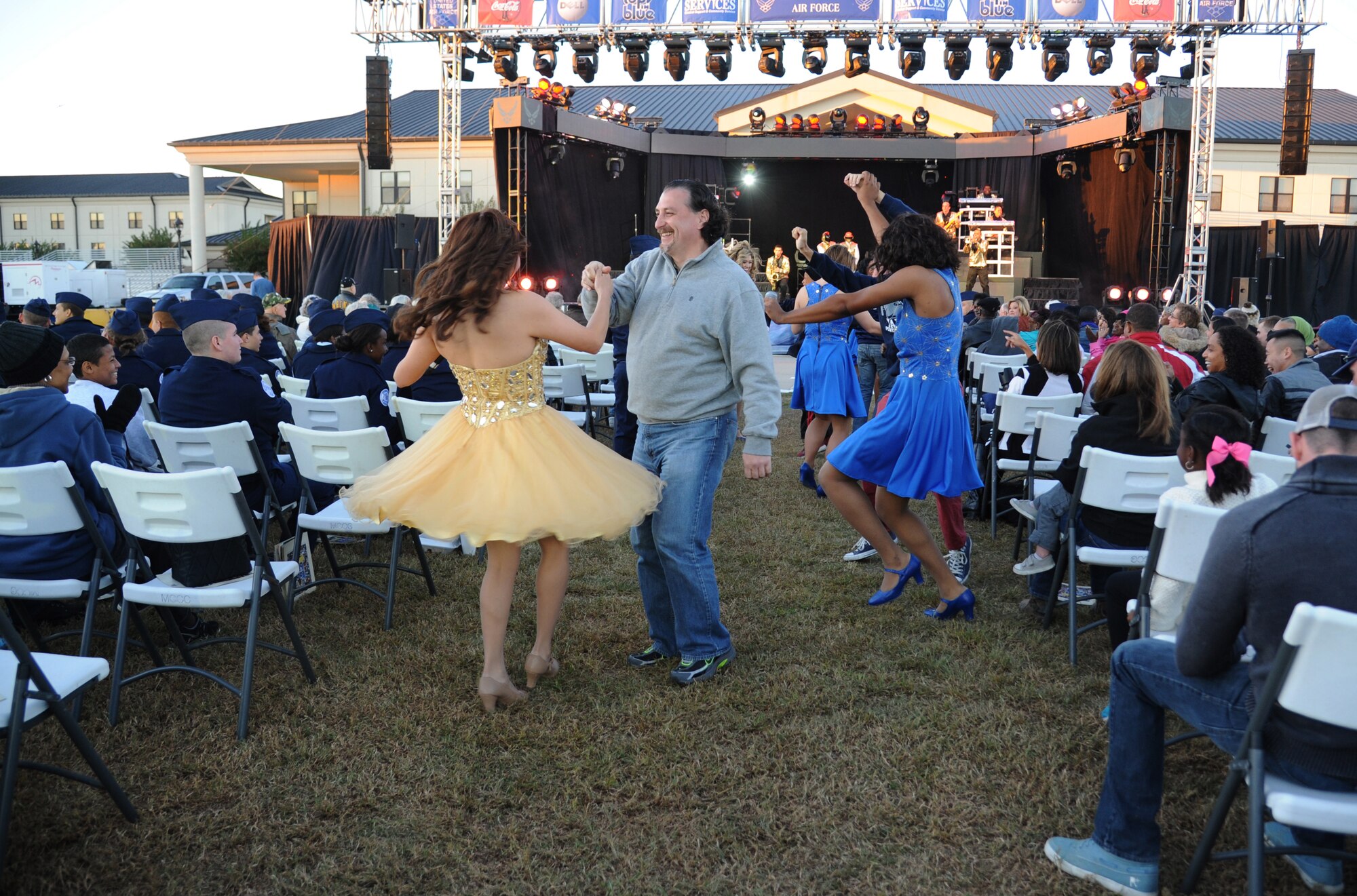 Retired Army Sgt. 1st Class Ricardo Mesa dances with Tops in Blue vocalist, Senior Airman Mayra Hernandez, during a performance by Tops in Blue during their 2014 World Tour Nov. 1, 2014, behind the Levitow Training Support Facility, Keesler Air Force Base, Miss.  Hundreds of Keesler Airmen, families and retirees watched and listened as the Tops in Blue members performed their diverse show celebrating 60 years of tradition.  Hernandez is a nutritional medicine journeyman from the 366th Medical Support Squadron, Mountain Home Air Force Base, Idaho. (U.S. Air Force photo by Kemberly Groue)
