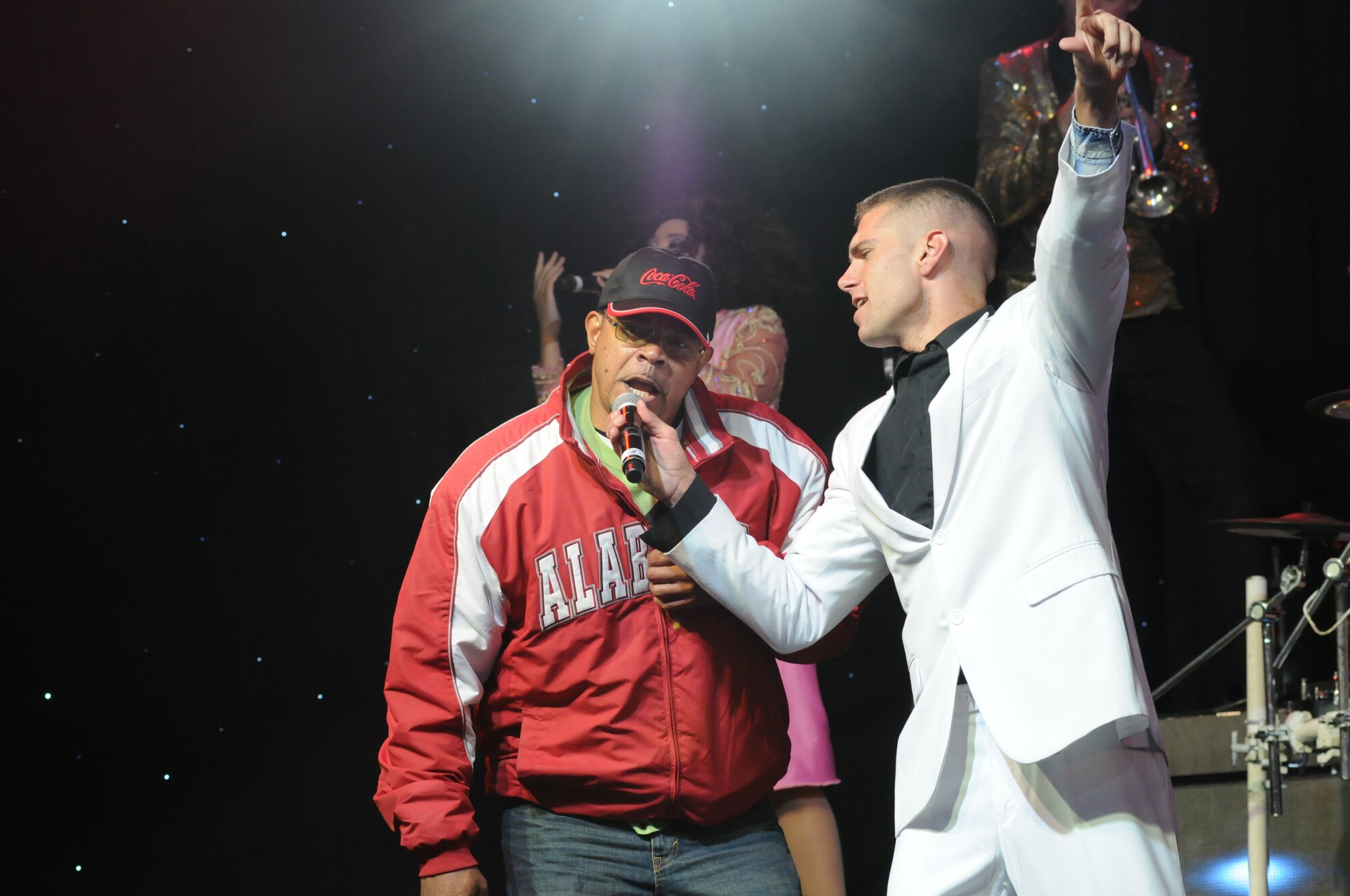 Retired Air Force Master Sgt. Timothy Taylor, Base Operations Support contractor, sings the lyrics to the song “Sweet Home Alabama” with the assistance of Tops in Blue vocalist, Senior Airman Jordan Premo, during a performance by Tops in Blue during their 2014 World Tour Nov. 1, 2014, behind the Levitow Training Support Facility, Keesler Air Force Base, Miss.  Hundreds of Keesler Airmen, families and retirees watched and listened as the Tops in Blue members performed their diverse show celebrating 60 years of tradition. Premo is a structural journeyman from the 11th Civil Engineer Journeyman, Joint Base Andrews-Naval Air Facility, Md. (U.S. Air Force photo by Kemberly Groue)
