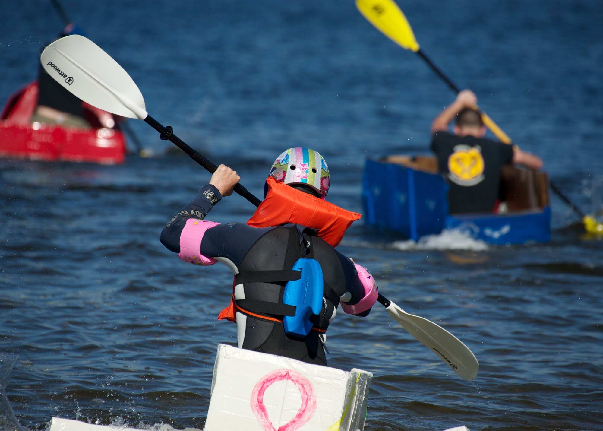 Competitors in the cardboard boat race fervently paddle toward the turn-around point during the 96th Operations Group Fun in the Sun at Post’l Point Oct. 31. Various events and competitions took place during the outing including volleyball, cornhole toss, tug-of-war and a cardboard boat race.  The annual event coincided with the 96th Test Wing’s Wingman Day which focused on strengthening relationships and showing respect and resiliency in the workplace. (U.S. Air Force photo/Sara Vidoni)