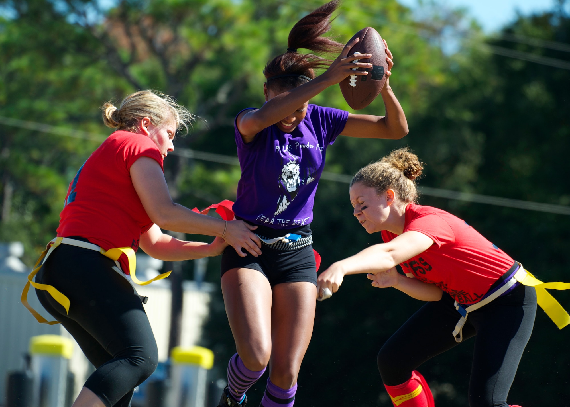 Senior Airman Elexa McCracken, of the 96th Logistics Readiness Squadron, attempts to bypass two 96th Force Support Squadron defenders during their powderpuff football game Oct. 31 at Eglin Air Force Base, Fla. LRS, the reigning champions, took home the win in a 13-0 victory by scoring a touchdown in each half and stopping FSS short in the red zone twice. McCracken scored the first touchdown for LRS. The annual powderpuff game coincided with the 96th Test Wing’s Wingman Day which focused on strengthening relationships and showing respect and resiliency in the workplace. (U.S. Air Force photo/Sara Vidoni)