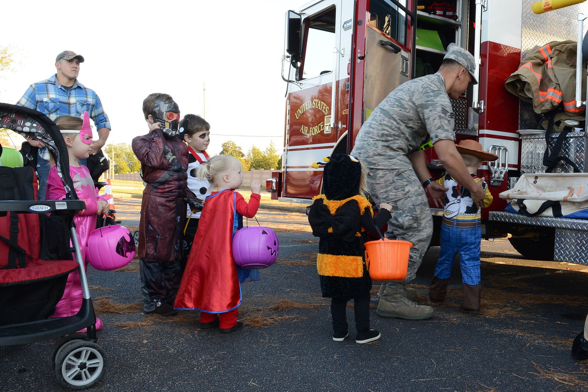 A 20th Civil Engineer Squadron firefighter lifts a child into a fire truck at Shaw Air Force Base, S.C., Oct. 31, 2014. The firefighters gave children tours of the truck after handing out candy for Halloween. (U.S. Air Force photo by Airman 1st Class Diana M. Cossaboom/Released)