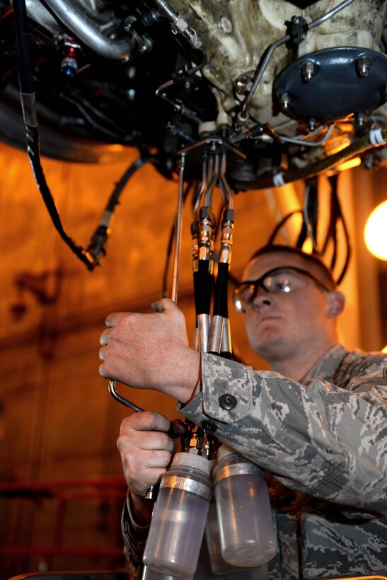 Airman 1st Class Benjamin Slye, 28th Maintenance Squadron engine test cell technician, attaches collection bottles to a B-1 bomber engine in the engine test cell at Ellsworth Air Force Base, S.D., Sept. 12, 2014. Bottles are used during testing to collect excess fluids from the engine to reduce leakage. (U.S. Air Force photo by Airman 1st Class Rebecca Imwalle/ Released) 