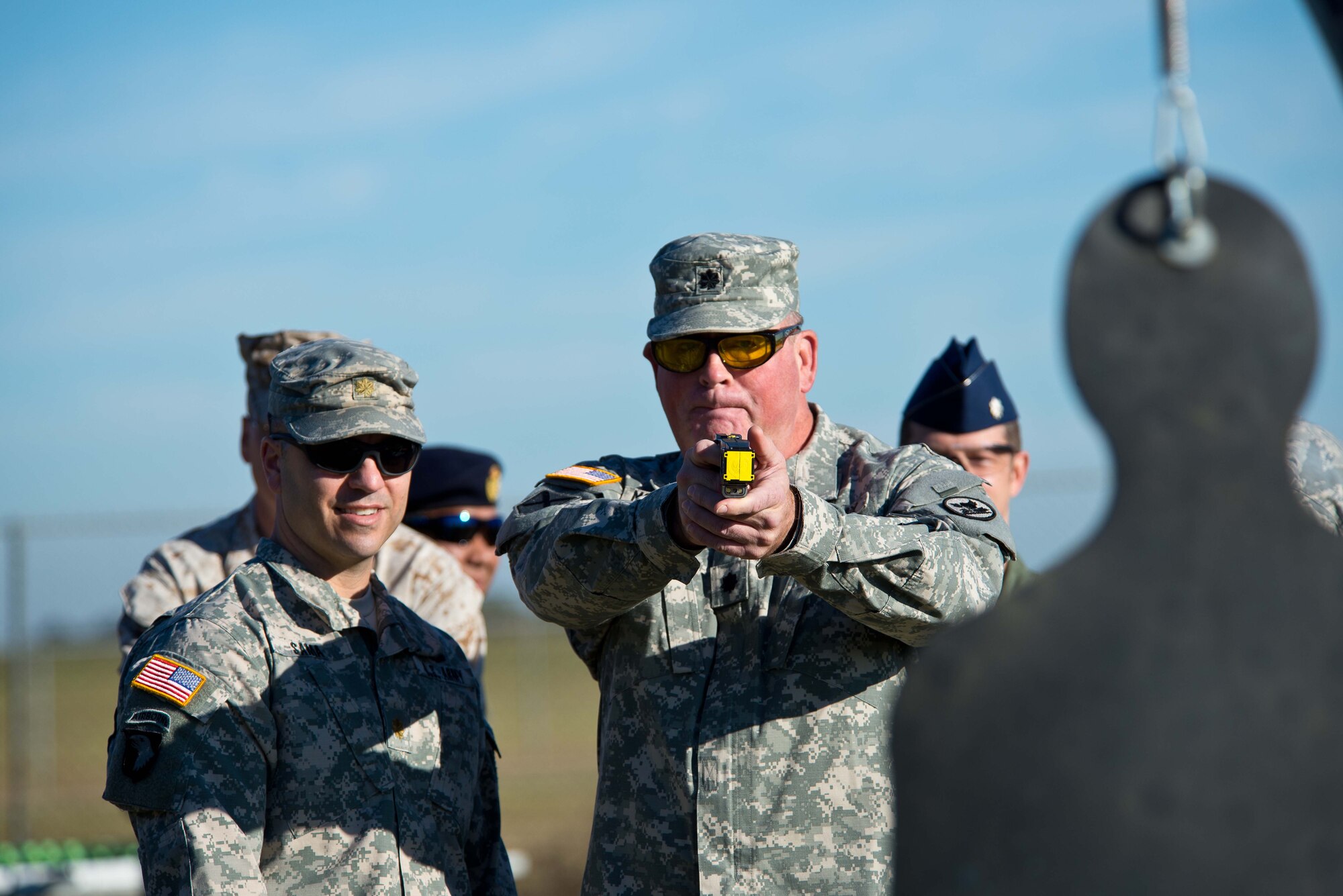 Army Maj. Jason Sama, Joint Non-Lethal Weapons Directorate education officer, oversees as Army Lt. Col. James McGlaughn, Air War College student, fires a stun gun at a target during the Non-lethal Weapons and Effects class at Maxwell Air Force Base, Alabama, Oct. 23, 2014. During the class, AWC students became familiar with about seven different types of non-lethal weapons. (U.S. Air Force photo by Donna L. Burnett)