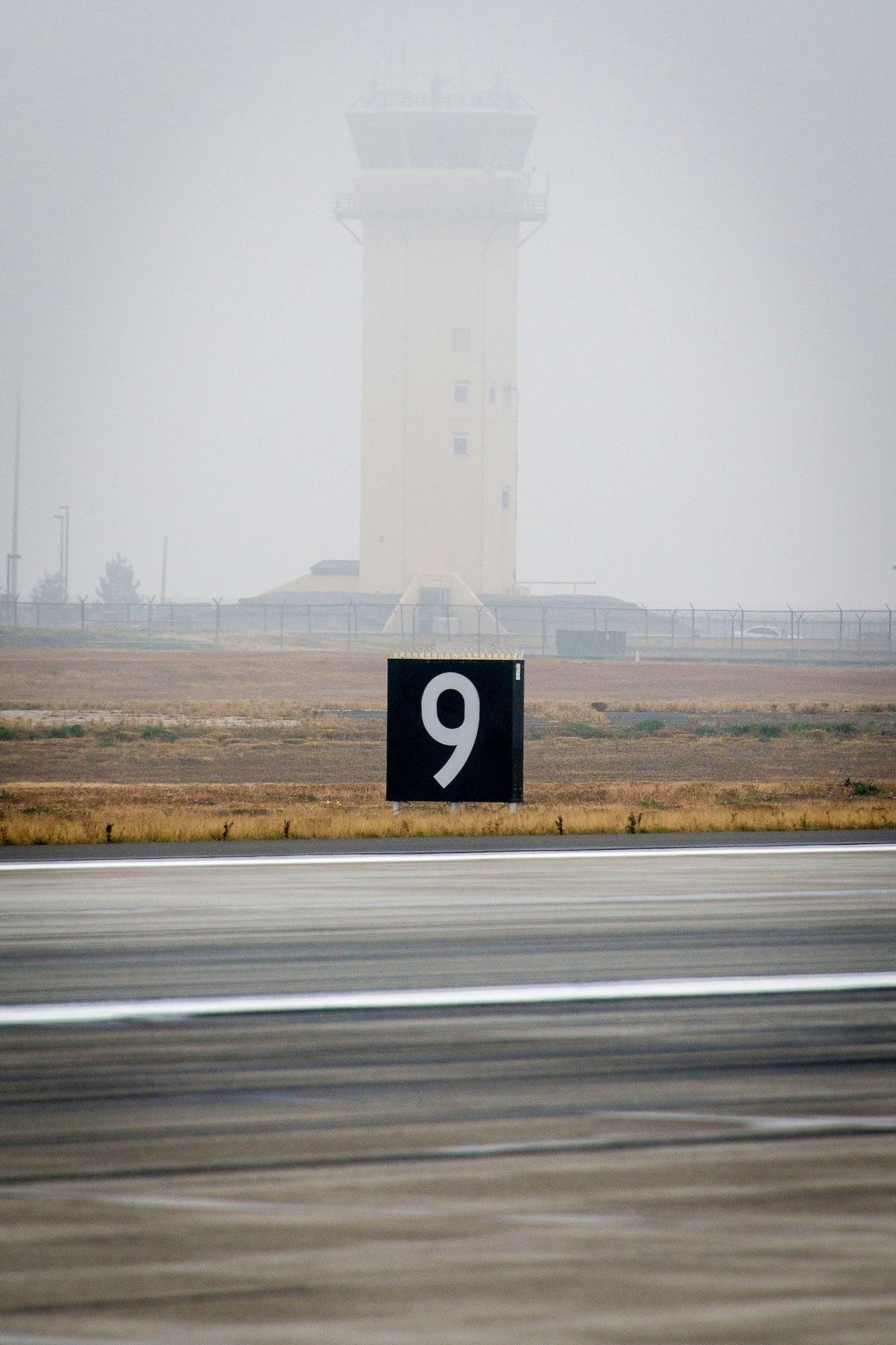 The Fairchild air traffic control tower stands watch as Airmen participate in a foreign object damage walk at Fairchild Air Force Base, Wash., Oct. 31, 2014. FOD walks ensure something as simple as a rock or pebble never has the chance of crippling a Team Fairchild jet. Members who find the legendary golden bolt receive a certificate and a day off from work. For more information regarding the wing’s FOD program, contact Tech. Sgt. Eric Gibson at (509) 247-4746. (U.S. Air Force photo/Staff Sgt. Benjamin W. Stratton)