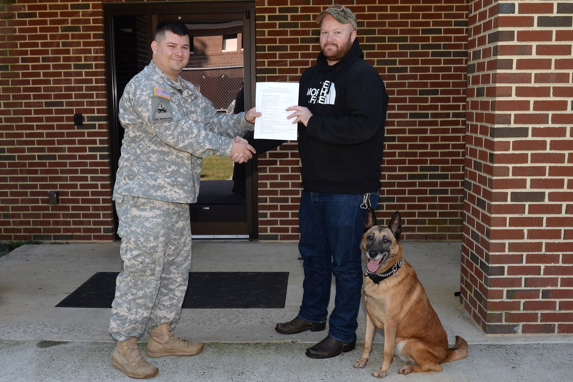 U.S. Army Staff Sgt. Jeffrey Michaud, 3rd Military Police Detachment kennel master, presents finalized adoptions paperwork to former U.S. Army Sgt. Matthew Bedortha, previously assigned to the 3rd Military Police Det., at Fort Eustis, Va., Oct., 31, 2014. Bedortha adopted Shay, a 10-year-old military working dog, whom he was partnered with for two and a half years. (U.S. Air Force photo by Staff Sgt. Teresa J. Cleveland/Released)