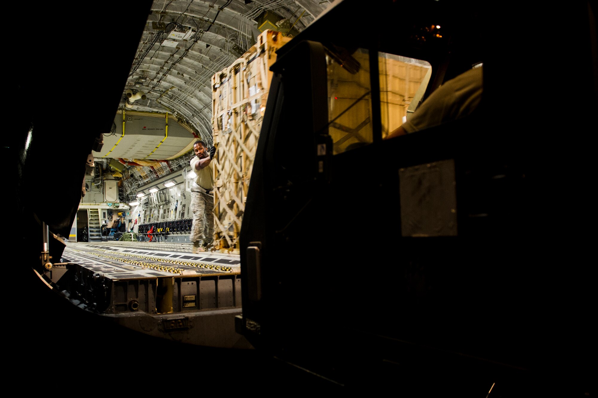 U.S. Air Force Tech. Sgt. Kiwan Edwards, an aircraft maintainer of the Joint Task Force-Port Opening of the 621st Contingency Response Wing stationed at Joint Base McGuire-Dix-Lakehurst, N.J., helps push a pallet from a C-17 Globemaster III onto a Halvorsen Loader here, during Operation United Assistance, Nov. 2, 2014. OUA is a Joint Forces Command-led operation to provide command and control, logistics, training and engineering support to the U.S. government’s efforts to contain the Ebola virus outbreak in West African nations. (U.S. Air Force photo by Staff Sgt. Gustavo Gonzalez/Released)