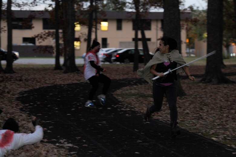 Perla Romo Knudstrup, wife of Lt. Cmdr. Timothy Knudstrup, Washington Navy Yard Strategic Systems Programs, runs from a “zombie” during the Zombie Apocalypse Run at Joint Base Andrews, Md, Oct 30, 2014. Military Families around the National Capital Region were invited to attend “Trunk or Treat” and the Zombie Apocalypse Run in celebration of Halloween.  (U.S. Air Force photo/ Senior Airman Nesha Humes)