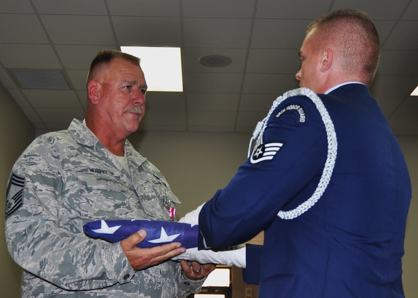 Chief Master Sgt. Kevin Murphy receives a folded flag from an Eglin Air Force Base honor guard member during his retirement ceremony Nov. 1 at Duke Field, Fla.  Surrounded by friends and family, Murphy said goodbye to the 919th Special Operations Wing and the Air Force after 33 years of service.  (U.S. Air Force photo/Dan Neely) 