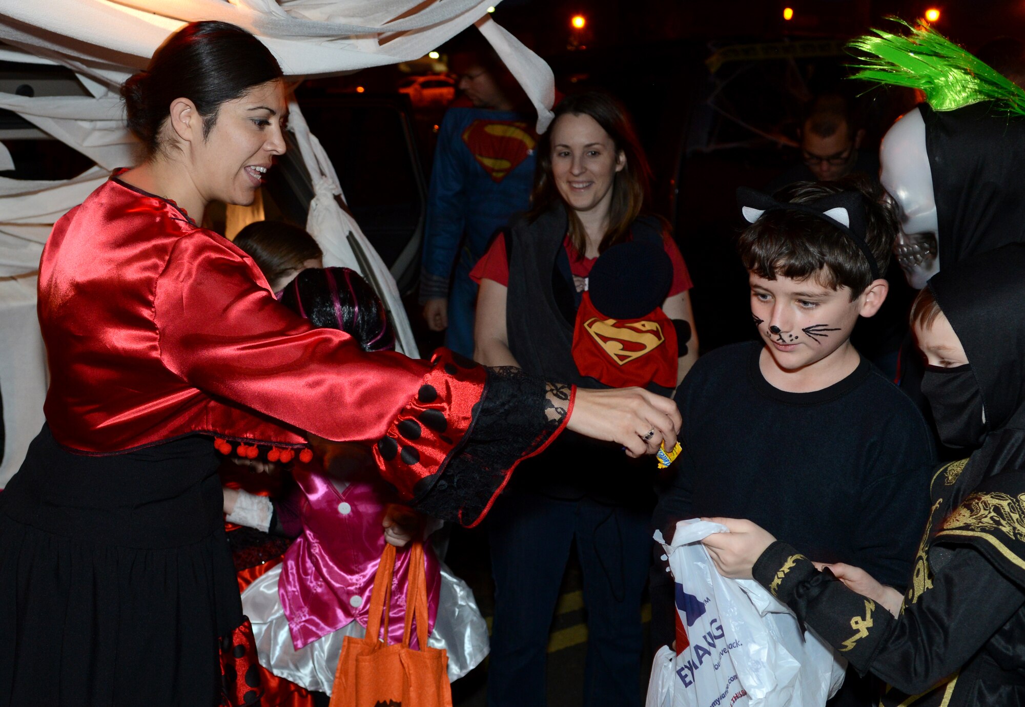 U.S. Air Force Tech. Sgt. Elizabeth DeArmond, left, 100th Air Refueling Wing administration section chief from Hemet, Calif., hands candy to children during the “Trunk or Treat” event Oct. 31, 2014, on RAF Mildenhall, England. Volunteers used the backs of their cars to create an easily accessible trick-or-treat venue for Team Mildenhall children. (U.S. Air Force photo by Airman 1st Class Dillon Johnston/Released) 