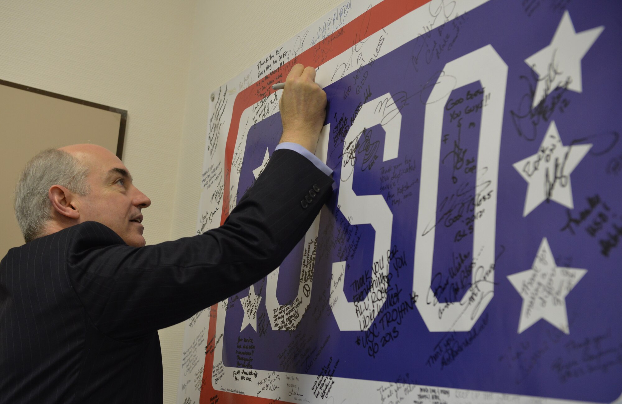 Dr. J.D. Crouch, USO’s president and CEO, endorses the USO banner after taking a tour of the Contingency Aeromedical Staging Facility on Ramstein Air Base, Germany, Oct. 28, 2014. Crouch and his wife came to Ramstein to visit different USOs in the region. (U.S. Air Force photo/Senior Airman Hailey Haux)