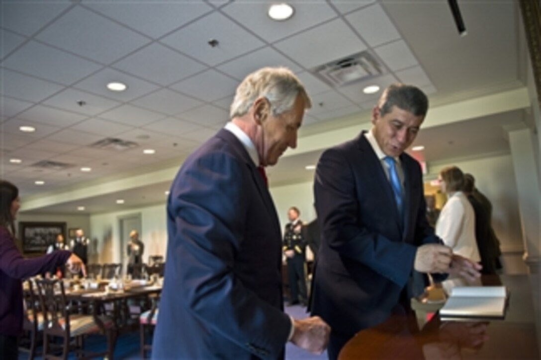 U.S. Defense Secretary Chuck Hagel, left, watches as Tunisian Defense Minister Ghazi Jeribi signs the guest book at the Pentagon, Nov. 3, 2014. The two defense leaders met to discuss issues of mutual importance.