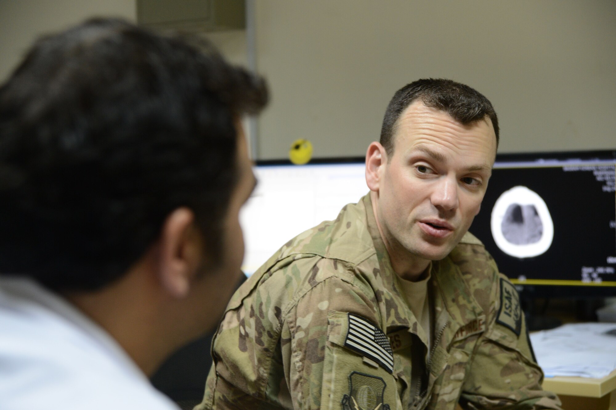 U.S. Air Force Maj. Jonathan Forbes, a neurosurgeon assigned to the 455th Expeditionary Medical Group, chats with an Afghan doctor working at the Korean Humanitarian hospital about a recent consultation of a potential Afghan patient at Bagram Airfield, Afghanistan. Forbes, a New Martinsville, West Virginia native is deployed from Travis Air Force Base, California and is responsible for performing 65 humanitarian surgeries during his six-month deployment. (U.S. Air Force photo by Master Sgt. Cohen A. Young/Released)