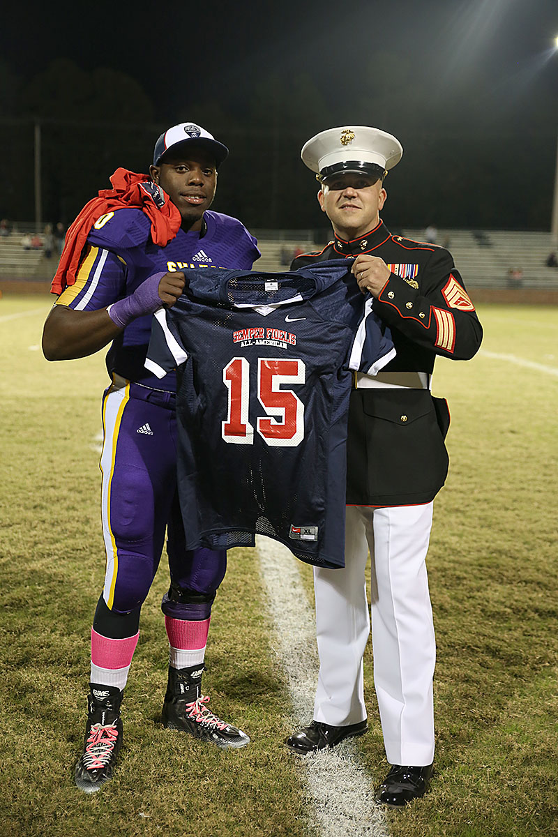 Staff Sgt. Travis Godley, canvassing recruiter, Marine Corps Recruiting Substation Lexington presents Jonathon Sutton, senior, Swansea High School with his Semper Fidelis All-American Bowl jersey during half-time of his last home football game at Swansea High School on Oct. 31, 2014.