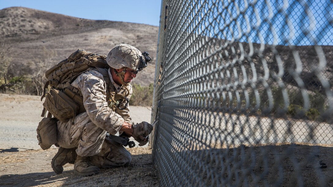 U.S. Marine Cpl. John Salazar places simulated explosives to breach a fence during a vertical-assault raid course aboard Camp Pendleton, Calif., Oct. 29, 2014. Salazar is an engineer with Lima Company, Battalion Landing Team 3rd Battalion, 1st Marine Regiment, 15th Marine Expeditionary Unit. The course teaches vertical assault techniques and the importance of working together as a cohesive unit during a raid. 