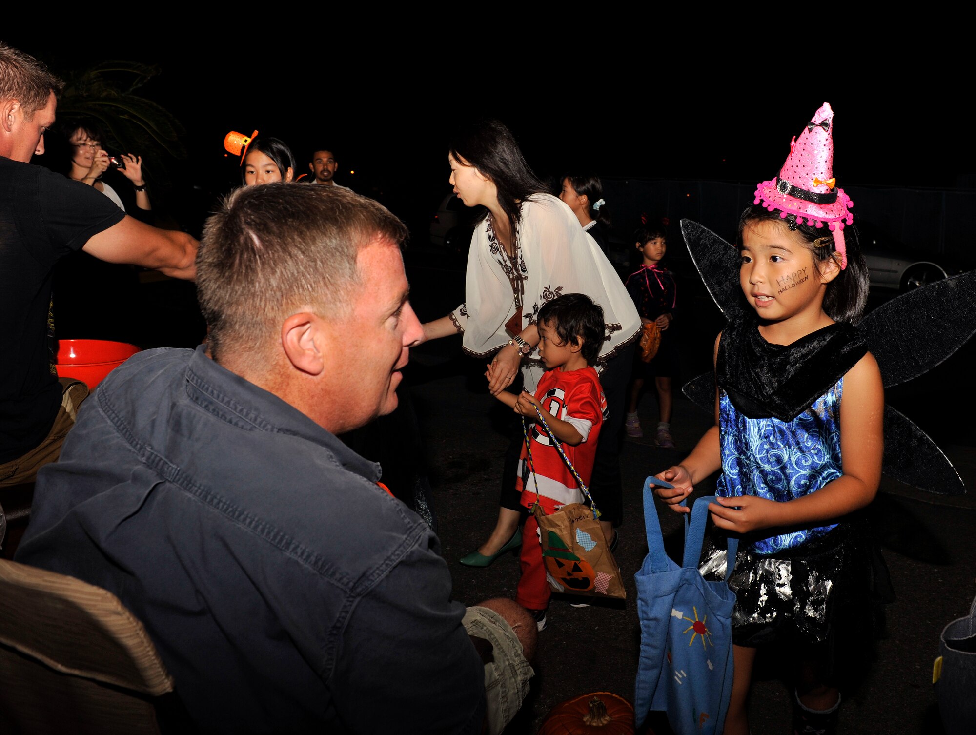 A Japanese trick-or-treater greets an on base resident in English after she receives candy at Stearly Heights during Halloween on Kadena Air Base, Japan, Oct. 31, 2014. Kadena has the opportunity to share the American tradition with their Japanese friends every year. (U.S. Air Force photo by Naoto Anazawa/Released)