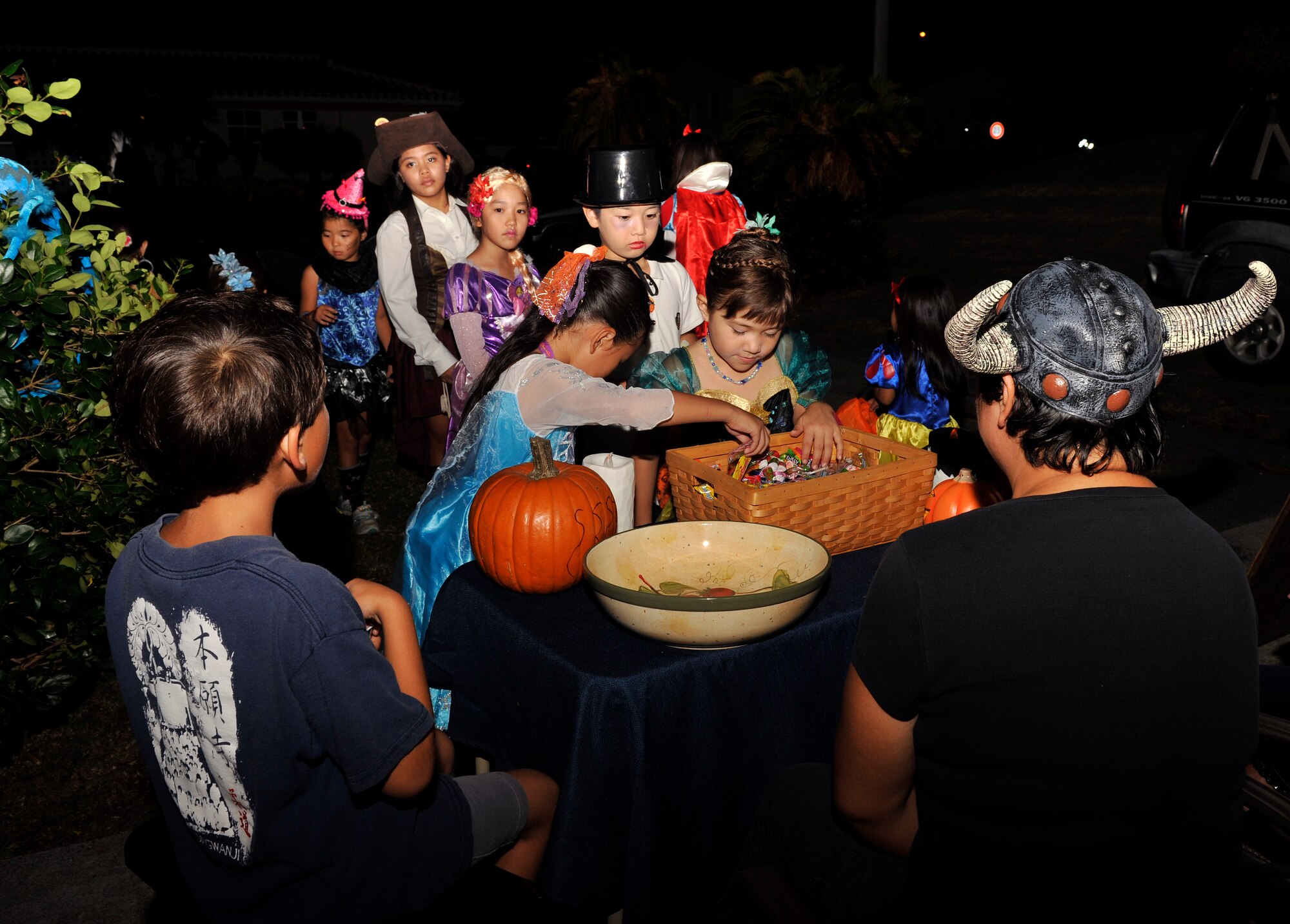 Japanese and American trick-or-treaters grab candy from the front of an on-base resident's house at Stearly Heights during Halloween on Kadena Air Base, Japan, Oct. 31, 2014. Traditionally, Kadena Air Base opens its gates to a selected group of Japanese neighbors to participate in the American Halloween custom of trick-or-treating in costume. (U.S. Air Force photo by Naoto Anazawa/Released)