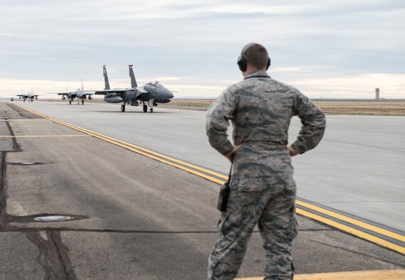 1st Lt. Daniel McGinnis-Welsh, 389th Aircraft Maintenance Unit assistant officer in-charge, looks on as F-15E Strike Eagles taxi down the landing strip at Mountain Home Air Force Base, Nov 4, 2014. McGinnis-Welsh evaluates performance during the Capstone training event. (U.S. Air Force photo by Airman 1st Class Jessica H. Smith/RELEASED) 