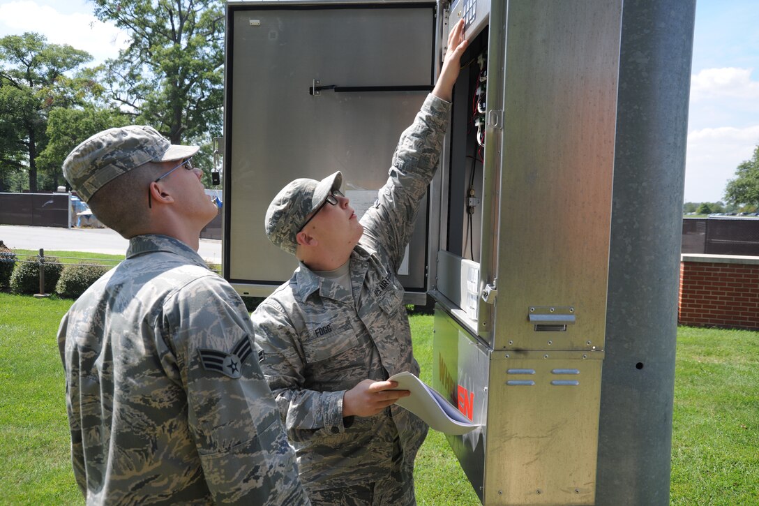 Airman 1st Class Ralph Fogg (right) and Senior Airman Robert Lewis, 744th Communication Squadron radio frequency technicians, examine motherboard components for a giant voice system at Joint Base Andrews, Md., on Aug. 26, 2014. The 744 CS is responsible for land-to-mobile communications, the giant voice and public address system. (U.S. Air Force photo/Airman 1st Class Joshua R. M. Dewberry)