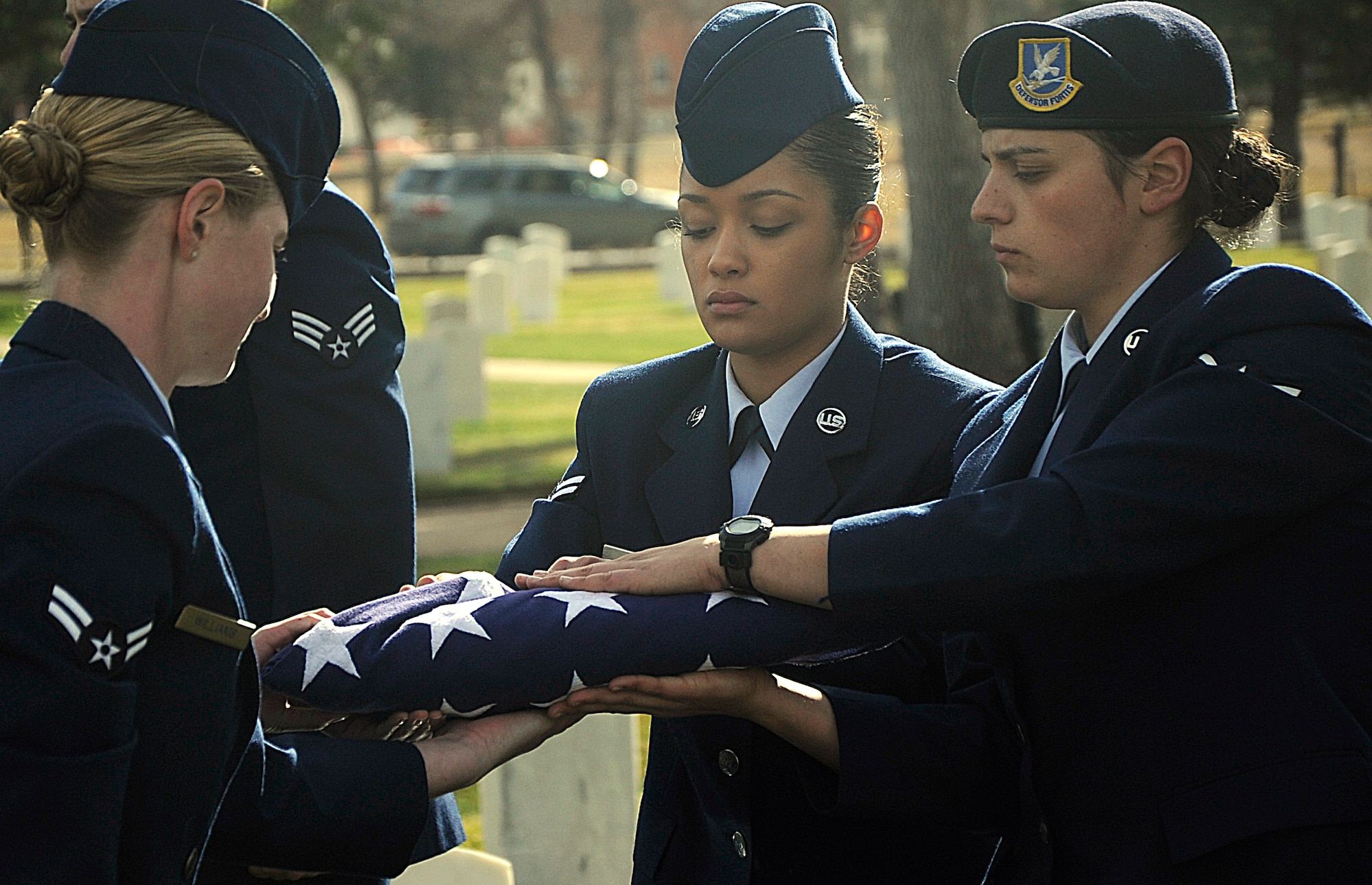 Airman 1st Class Carissa Williams, Airman 1st Class Jennifer Love, 90th Security Forces Squadron, and Airman 1st Class Tangie Reid, 90th Force Support Squadron, perform the final steps of folding a flag during a graduation ceremony Oct. 31 at the F.E. Warren Air Force Base, Wyo. The ceremonial folding of a flag requires teamwork and coordination to complete. (U.S. Air Force photo by Airman 1st Class Brandon Valle)