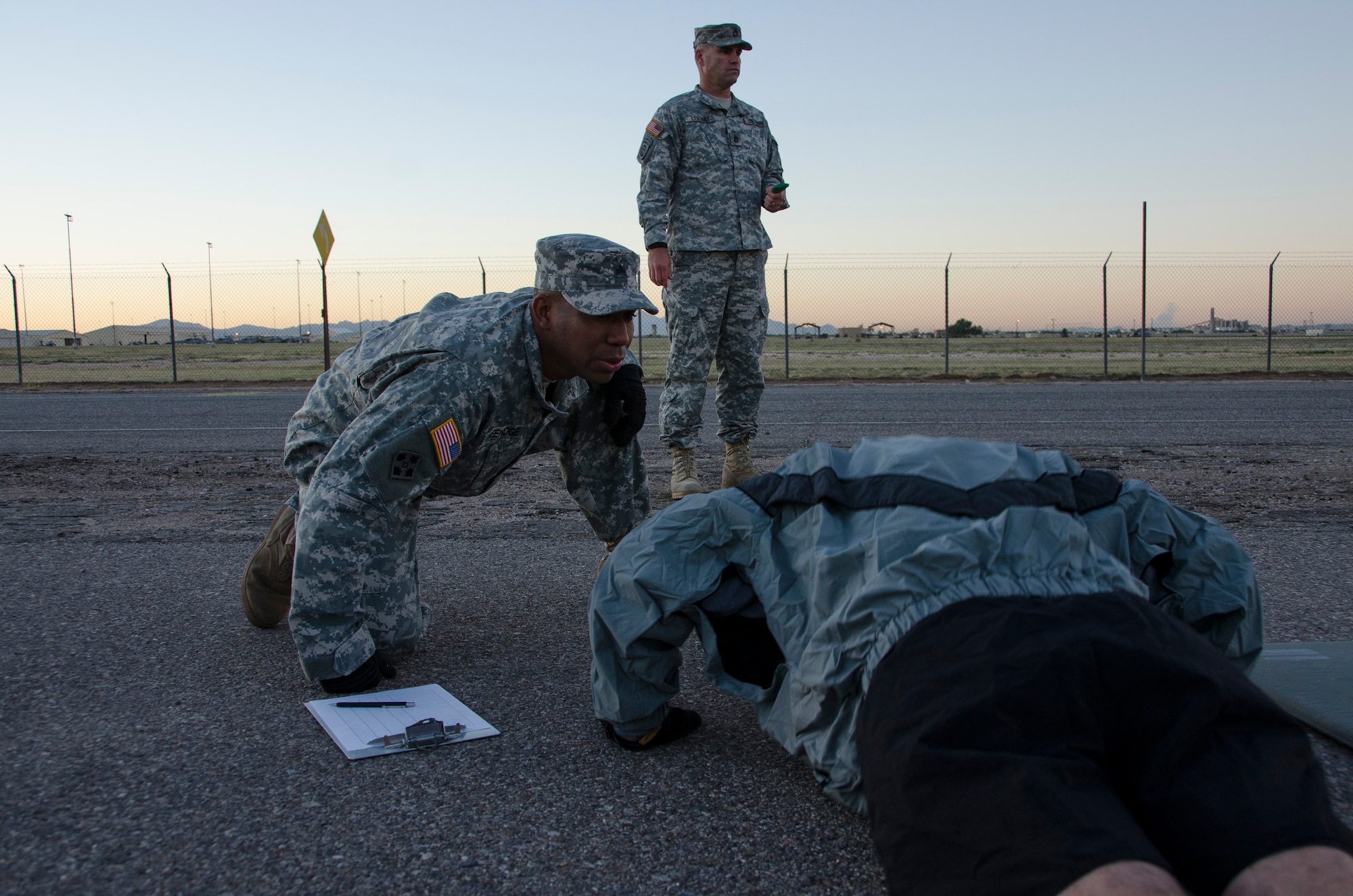 Sgt. Kelly Greenidge, 1st Battlefield Coordination Detachment Fire Support NCO, observes as a member begins the push-up portion of the Army physical fitness test at Davis-Monthan AFB, Ariz., Nov. 4, 2014. During this portion Greenidge is ensuring the member breaks a 90 degree angle, as well as telling them their current count. (U.S. Air Force photo by Staff Sgt. Adam Grant/Released)