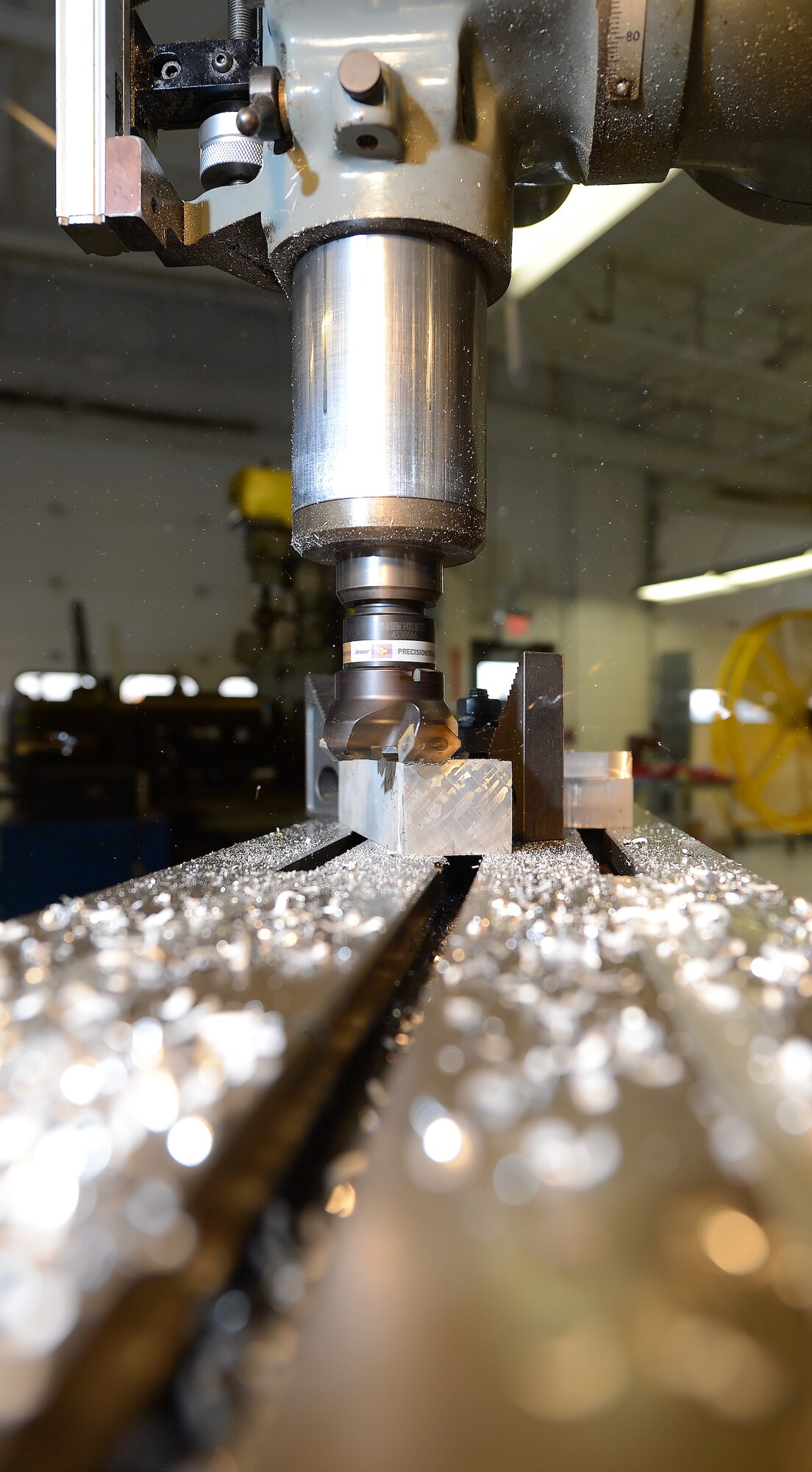 Aluminum shavings fly through the air and collect on the mill table as a block of aluminum is milled by a technician from the 436th Maintenance Squadron???s Aircraft Metals Technology Shop Oct. 31, 2014, at Dover Air Force Base, Del. This shop fabricates parts to keep Air Force aircraft operational at the lowest possible cost. (U.S. Air Force photo/Greg L. Davis)