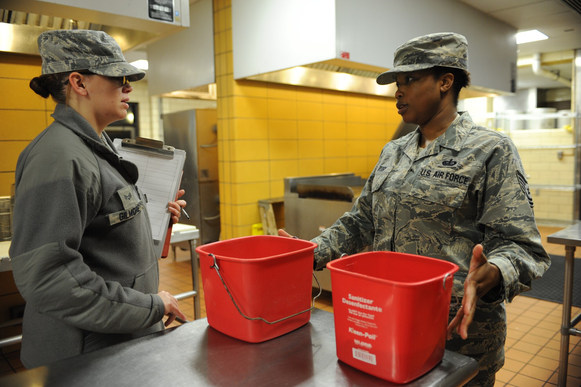 Senior Airman Jessica Gilmore, 5th Medical Operations Squadron public health technician, speaks with Tech. Sgt. Kymdra Toby, 5th Force Support Squadron dining facility manager concerning proper sanitation solution chemical levels at the dining facility on Minot Air Force Base, N.D., Oct. 28, 2014. Inspections at the dining facility are conducted monthly to ensure that proper food preparation and handling procedures are being met. (U.S. Air Force photo/Senior Airman Stephanie Morris)