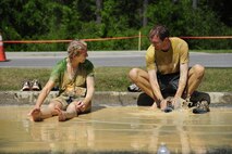 A couple takes a break and washes off after the Emerald Coast MudRun for Orphans in Niceville Fla., May 17. Active duty and reserve service members came out to get dirty in either the morning or afternoon 5K challenges. The participants could run, crawl, climb, slide, and scale their way through this adventure race.  (U.S. Air Force photo/Tech. Sgt. Jasmin Taylor)