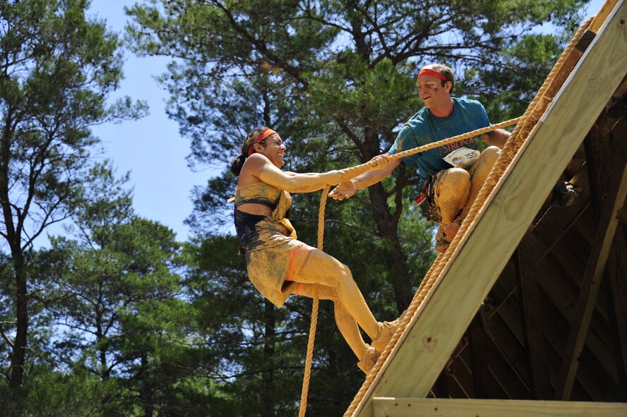 A competitor reaches to help his teammate up the rope at the Emerald Coast MudRun for Orphans in Niceville Fla., May 17. Active duty and reserve service members came out to get dirty in either the morning or afternoon 5K challenges. The participants could run, crawl, climb, slide, and scale their way through this adventure race.  (U.S. Air Force photo/Tech. Sgt. Jasmin Taylor)