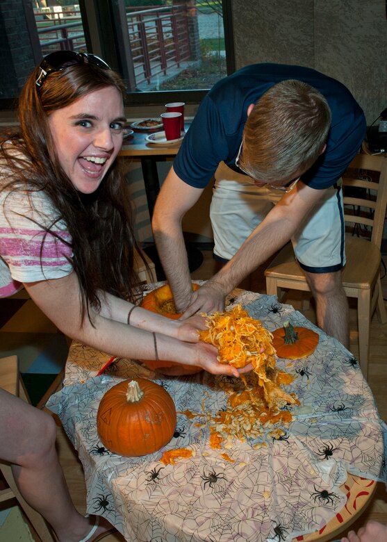 PETERSON AIR FORCE BASE, Colo. – Sara Garrett, 21st Dental Squadron dental lab technician, picks up pumpkin guts while Shawn Gadwa, 21st Communications Squadron cyber transportation specialist, cleans out the pumpkin at the chapel’s second annual pumpkin carving contest at the Cyber Café Oct. 29. Five teams participated in the pumpkin carving contest sponsored by the Peterson AFB Chapel. (U.S. Air Force photo/Airman 1st Class Rose Gudex)