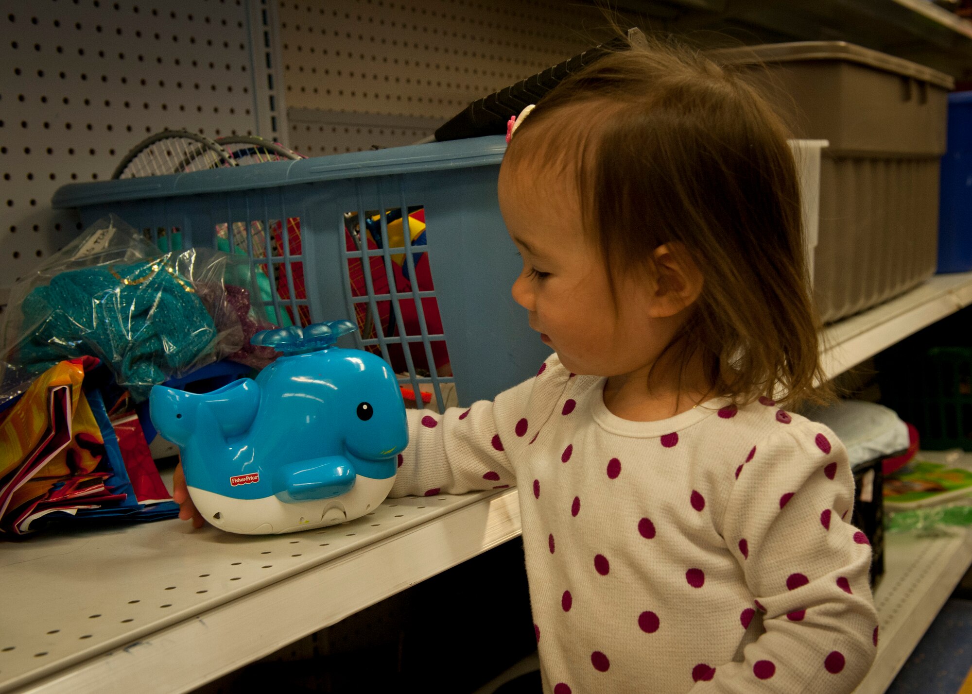 PETERSON AIR FORCE BASE, Colo. – Ellisia Julian, 2, checks out a toy amongst the shelves at the Airman’s Attic Oct. 29. The Airman’s Attic is a place where Airmen in grades E-5 and below can get household goods, clothes, children’s toys and miscellaneous items for free. Military uniforms are also available for free to all ranks. (U.S. Air Force photo/Airman 1st Class Rose Gudex)