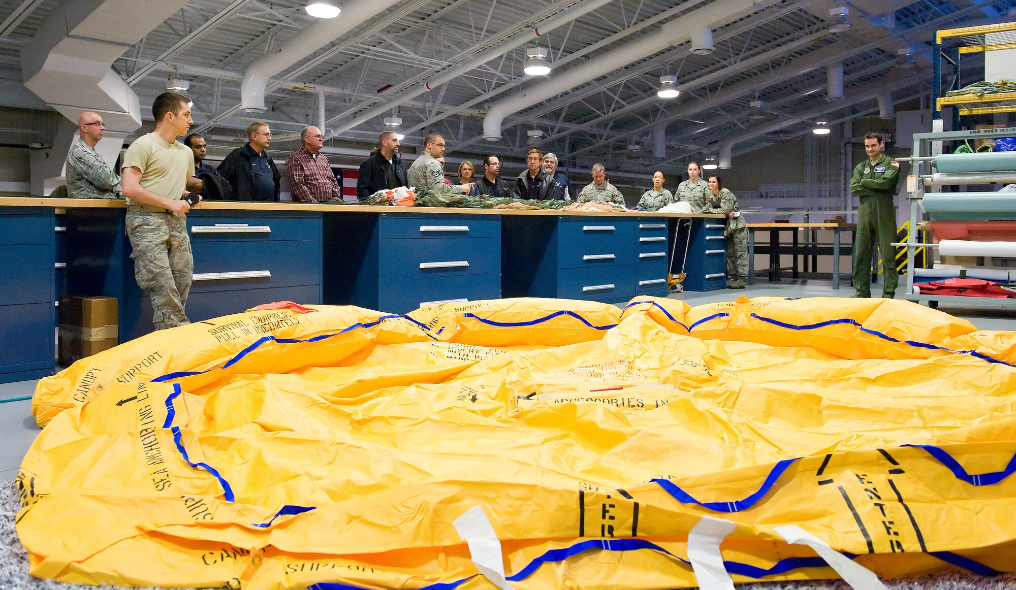Staff Sgt. Jacob Johnson, 436th Operations Support Squadron aircrew flight equipment training instructor, center, briefs Team Dover honorary commanders on the inspection process of a C-17 Globemaster III 46-man life raft Oct. 29, 2014, at Dover Air Force Base, Del. Airman 1st Class Casey Tierney, 436th OSS aircrew flight equipment technician, left, was in the process of performing an inflation test as part of the inspection process that is due every four years. (U.S. Air Force photo/Roland Balik)