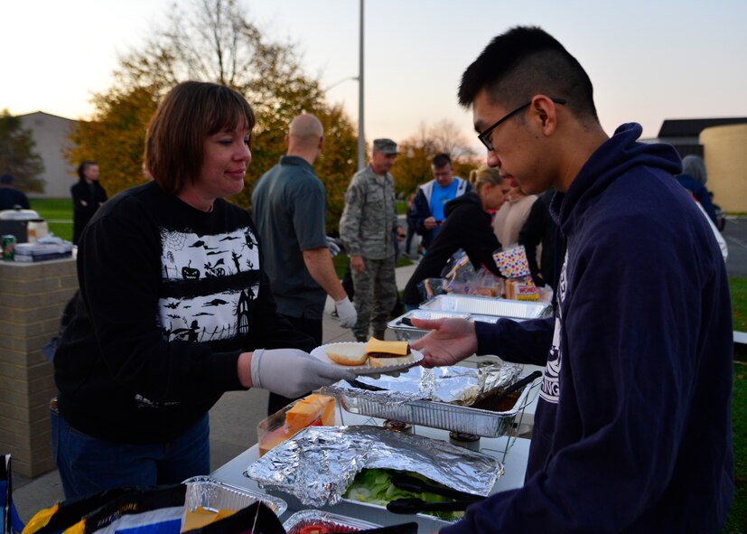 Tech. Sgt. Melinda Santiago, 436th Wing Staff reliance program manager, serves food to Airman 1st Class Zhi Wen, 436th Operations Support Squadron airfield management, during a combined dinner and “Trunk-or-Treat” event sponsored by the Chief’s Group and Airmen Dorm Council Oct. 30, 2014, at Dover Air Force Base, Del. Hamburgers and hotdogs were served alongside with soft drinks and chips for Airmen living in the dorms. (U.S. Air Force photo/Airman 1st Class William Johnson)