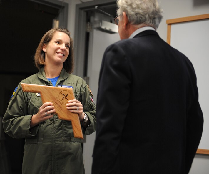 U.S. Air Force Lt. Col. Beth Makros, 394th Combat Training Squadron commander, presents retired U.S. Air Force Master Sgt. Amiel Guitz with a farewell gift during his retirement ceremony at Whiteman Air Force Base, Mo., Oct. 31, 2014. Guitz initially joined the U.S. Army Air Corps at the age of 15 by altering his name and date of birth on his birth certificate. (U.S. Air Force photo by Airman 1st Class Joel Pfiester/Released)